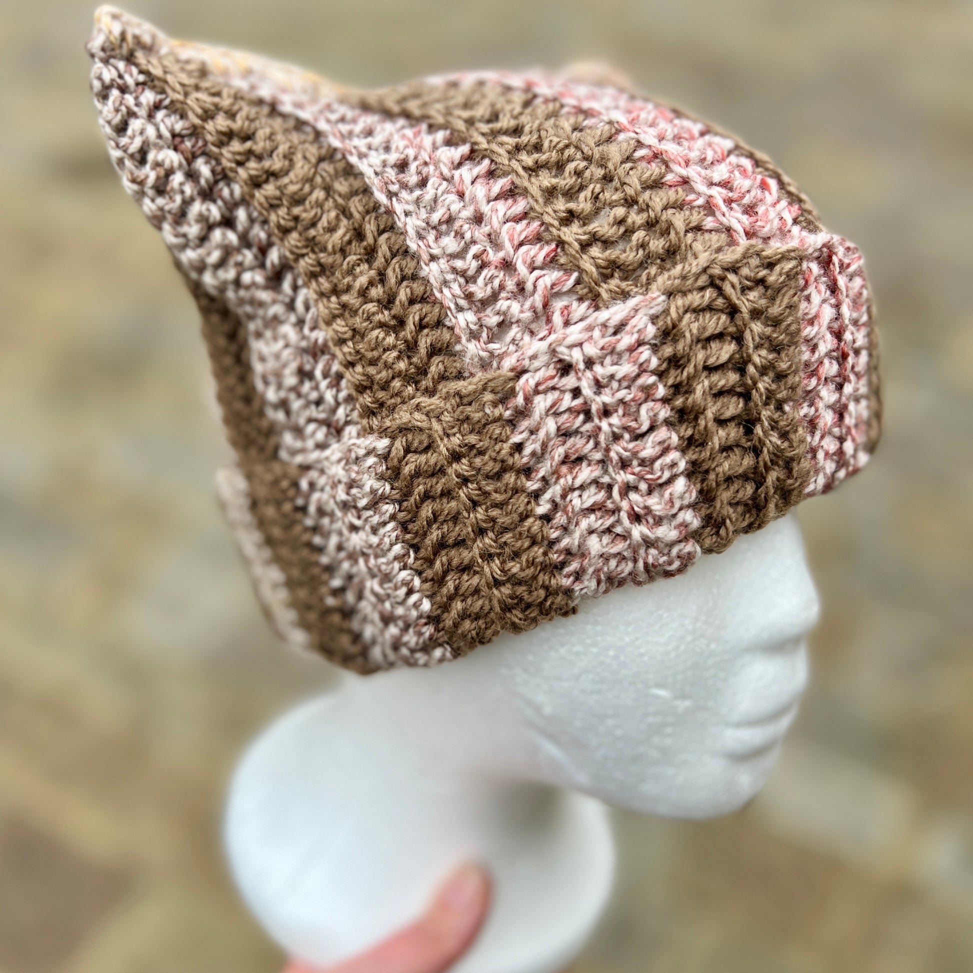 Knitted beanie on a mannequin head with a blurred natural background